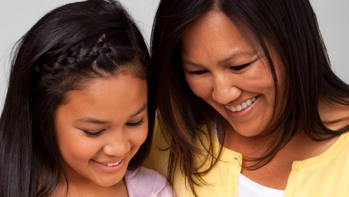 Mother and daughter together, smiling reading 